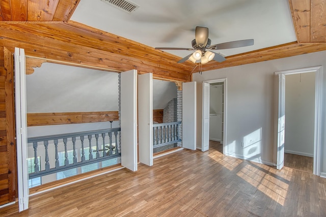 unfurnished bedroom featuring ceiling fan, wood-type flooring, a spacious closet, and lofted ceiling