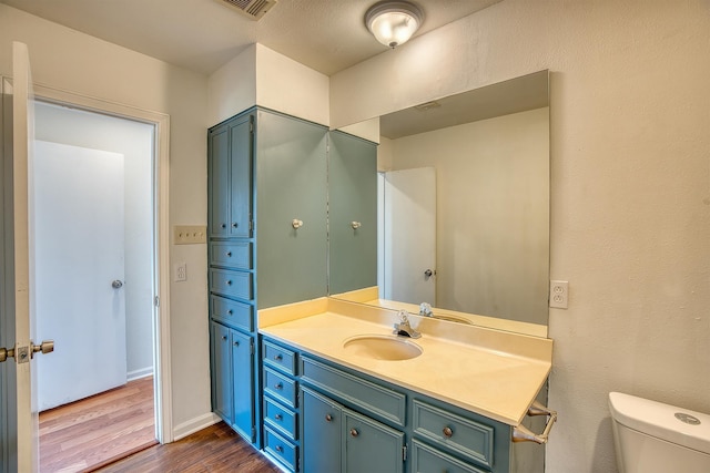 bathroom with toilet, vanity, and wood-type flooring