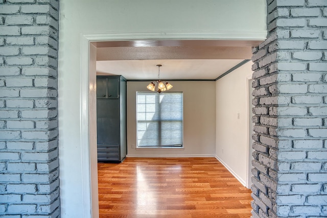 unfurnished dining area with crown molding, light hardwood / wood-style flooring, and a notable chandelier