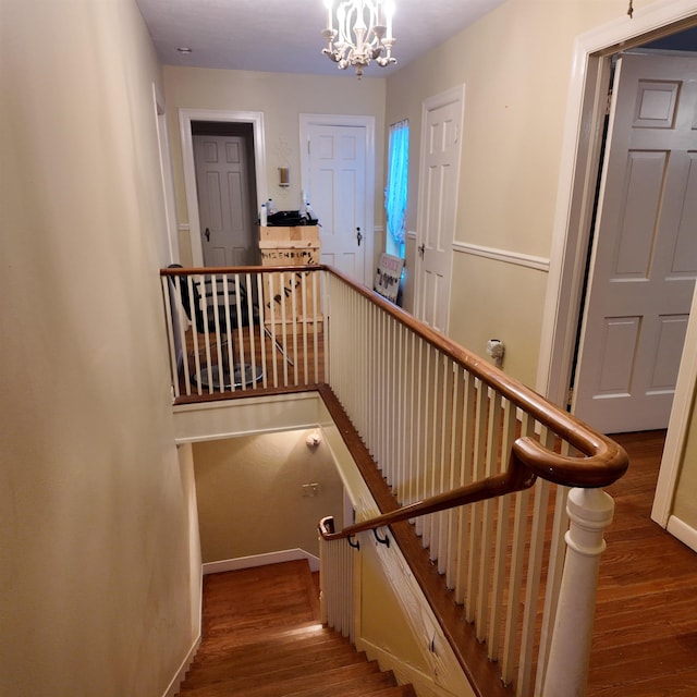 staircase featuring hardwood / wood-style flooring and a notable chandelier