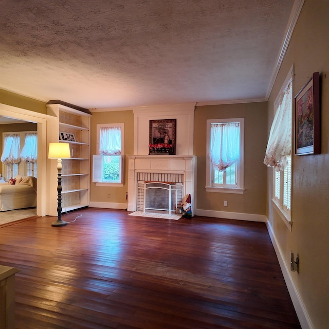 unfurnished living room featuring a textured ceiling, a fireplace, plenty of natural light, and crown molding