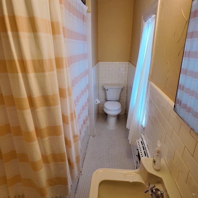 bathroom with tile patterned floors, toilet, and tile walls