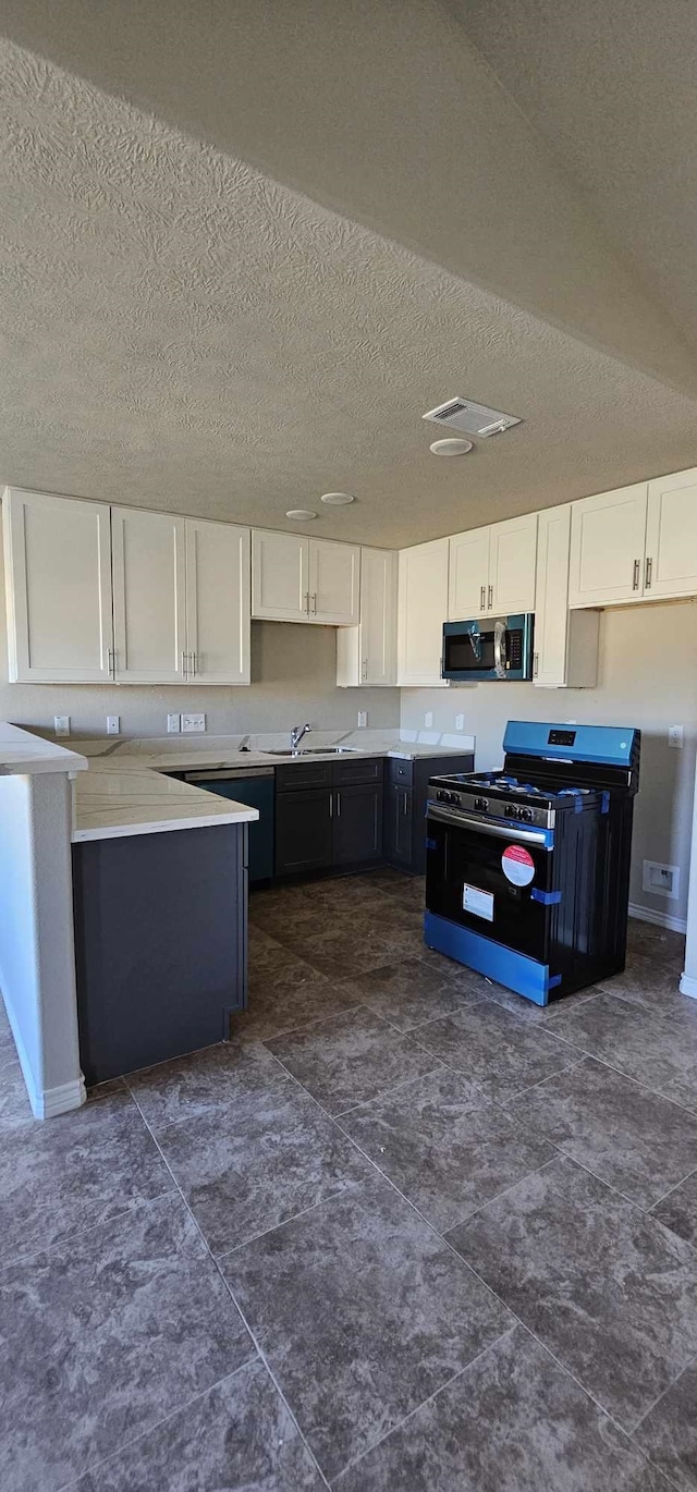 kitchen with white cabinets, black range with gas stovetop, sink, and a textured ceiling