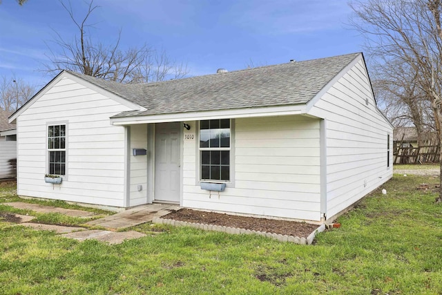 view of front of house with a shingled roof and a front lawn