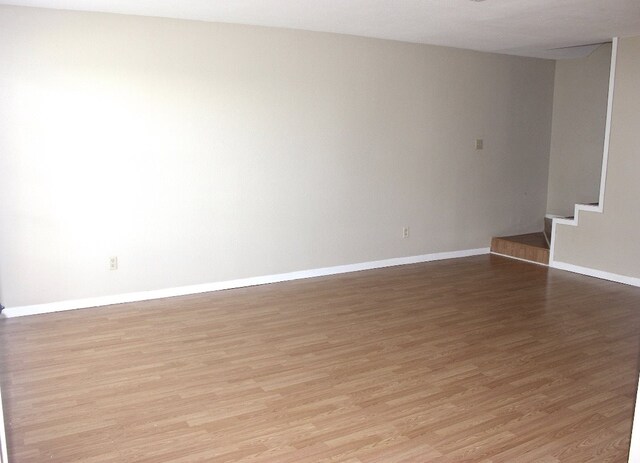 8642 Glen Meadow Ln, Beaumont, TX 77706 - unfurnished room featuring light wood-style floors, stairway, and baseboards