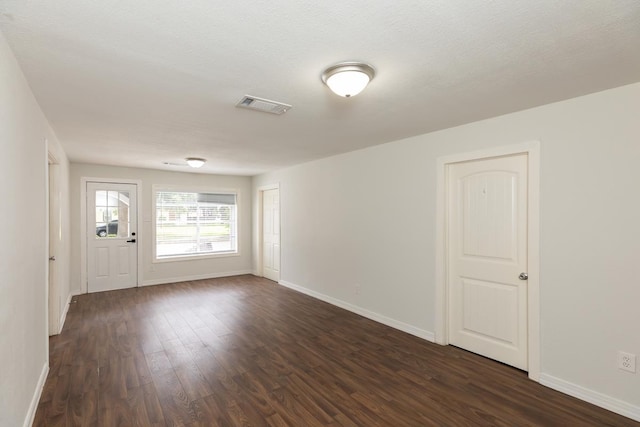 unfurnished room with dark wood-type flooring and baseboards