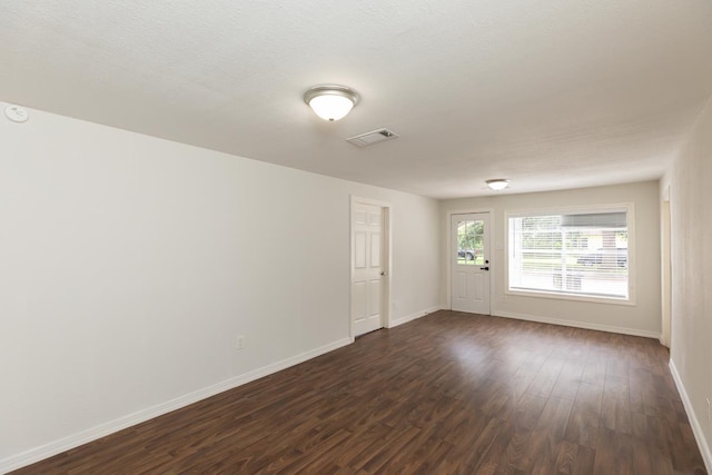 spare room with dark wood-style flooring and baseboards