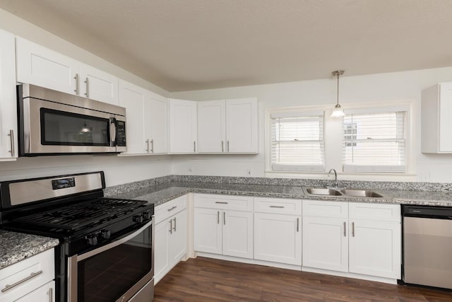 kitchen with stainless steel appliances, a sink, white cabinets, dark wood-style floors, and light stone countertops