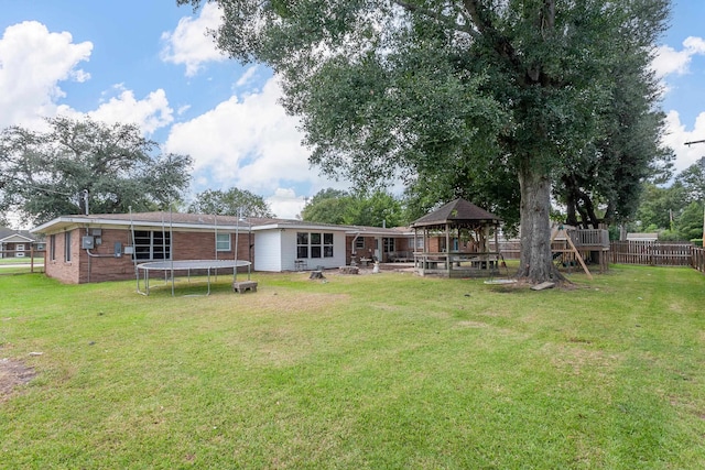 back of property with a gazebo, a trampoline, and a yard