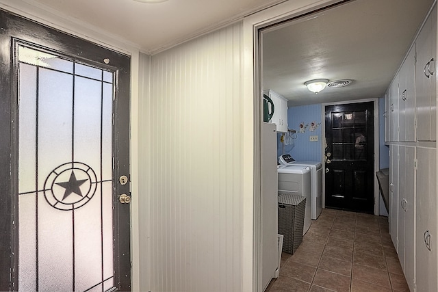 clothes washing area with separate washer and dryer, dark tile patterned floors, and cabinets