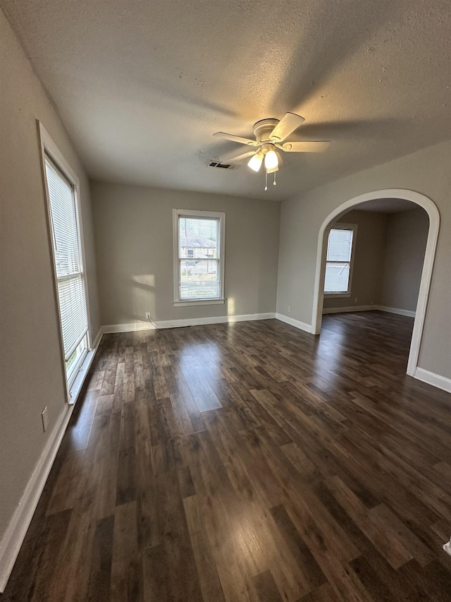 empty room with dark hardwood / wood-style flooring, ceiling fan, and a textured ceiling