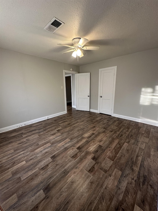 empty room featuring ceiling fan, dark hardwood / wood-style floors, and a textured ceiling