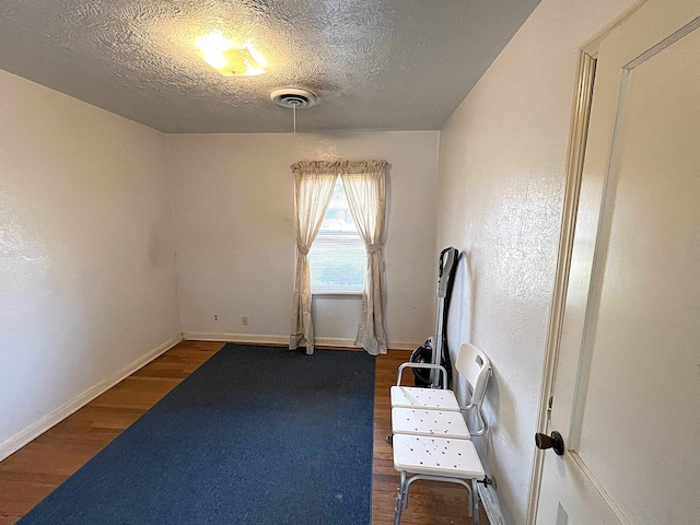 207 Elm St, Silsbee, TX 77656 - exercise room featuring wood finished floors, a textured ceiling, and baseboards