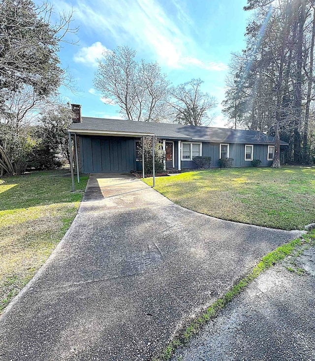 207 Elm St, Silsbee, TX 77656 - ranch-style house with concrete driveway, board and batten siding, a chimney, and a front yard