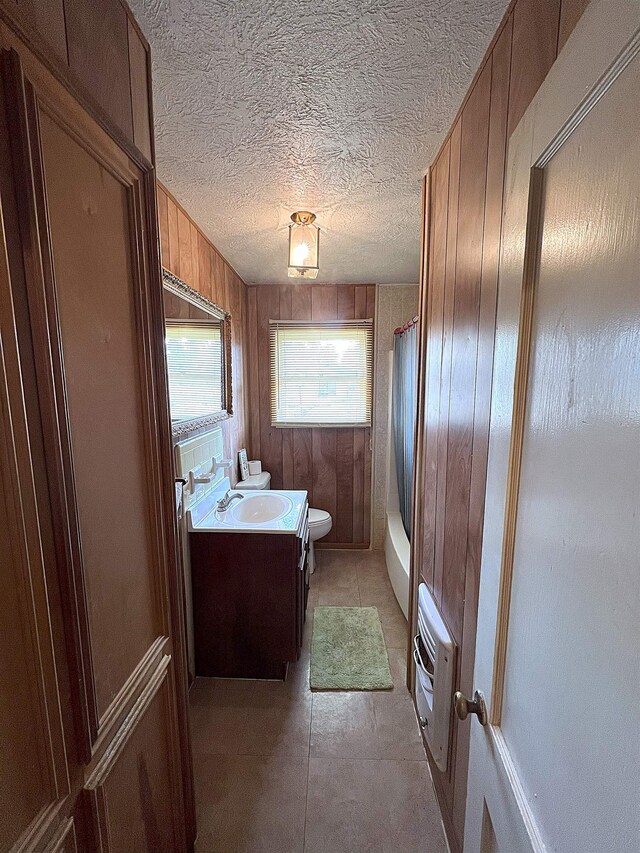 207 Elm St, Silsbee, TX 77656 - bathroom featuring toilet, vanity, wooden walls, a textured ceiling, and heating unit