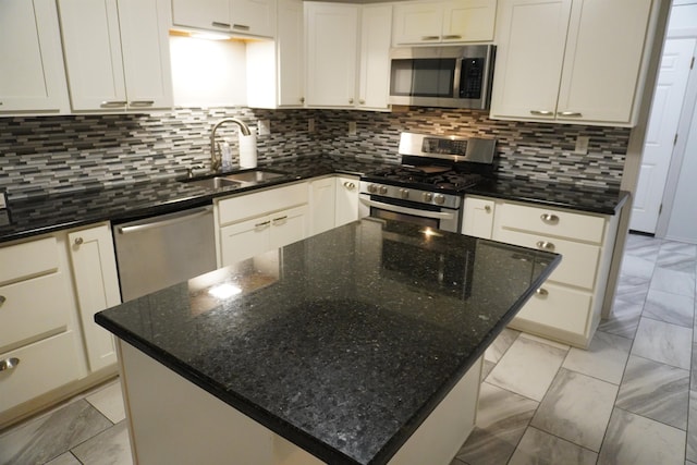 kitchen featuring white cabinets, sink, stainless steel appliances, and dark stone counters