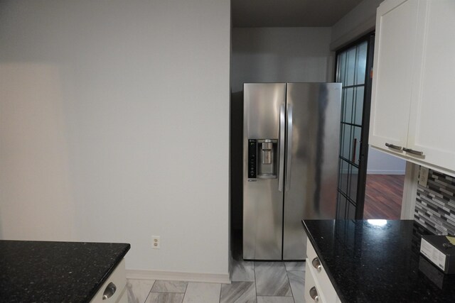 interior space featuring stainless steel fridge with ice dispenser and dark stone countertops