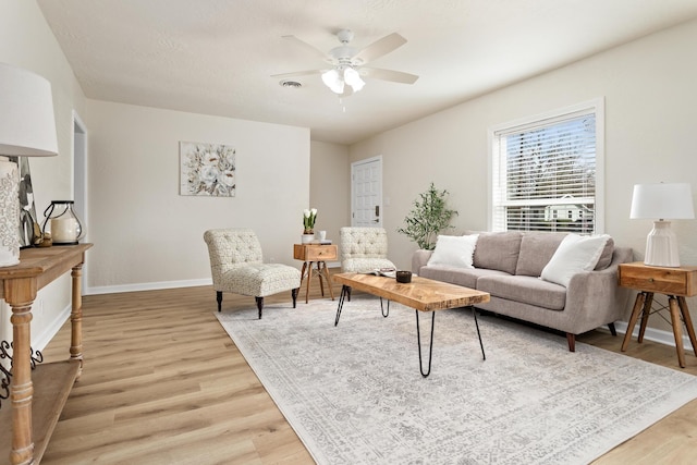 living room featuring baseboards, light wood finished floors, and ceiling fan