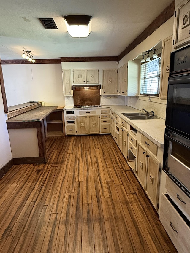 kitchen with sink, dark wood-type flooring, double oven, stainless steel gas stovetop, and decorative backsplash