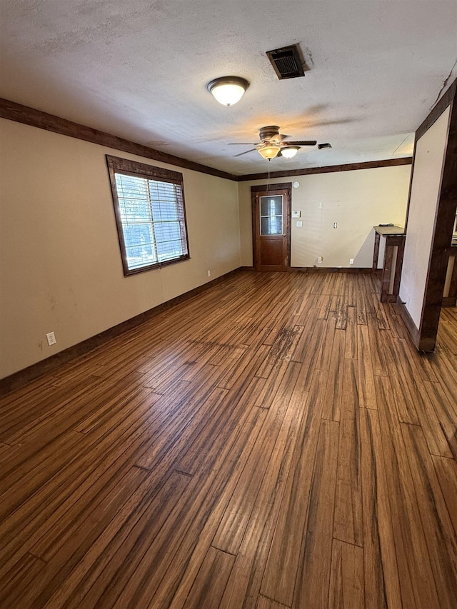 spare room featuring ceiling fan, dark hardwood / wood-style flooring, ornamental molding, and a textured ceiling