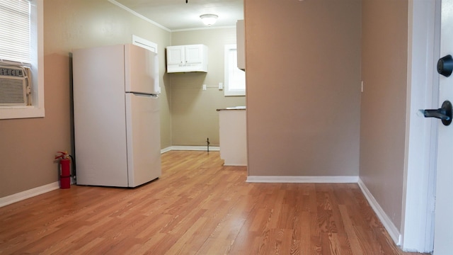 interior space with white cabinets, white fridge, crown molding, and light hardwood / wood-style floors