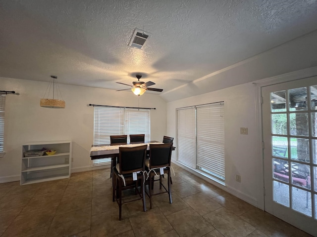 dining room with ceiling fan, dark tile patterned floors, a textured ceiling, and vaulted ceiling