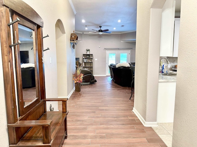 hallway with sink, light wood-type flooring, french doors, and ornamental molding