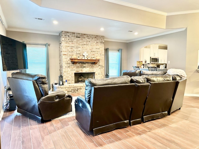 living room featuring a brick fireplace and crown molding