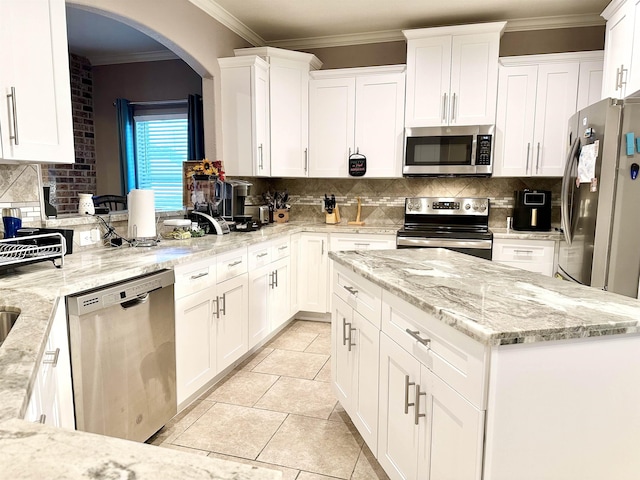 kitchen with decorative backsplash, white cabinetry, light stone countertops, and appliances with stainless steel finishes