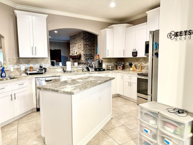 kitchen featuring white cabinets, decorative backsplash, a kitchen island, and appliances with stainless steel finishes