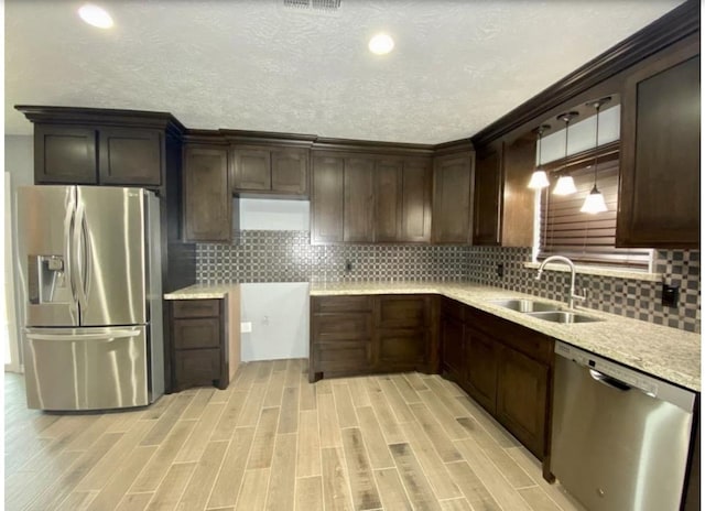 kitchen with pendant lighting, sink, appliances with stainless steel finishes, light hardwood / wood-style floors, and dark brown cabinetry