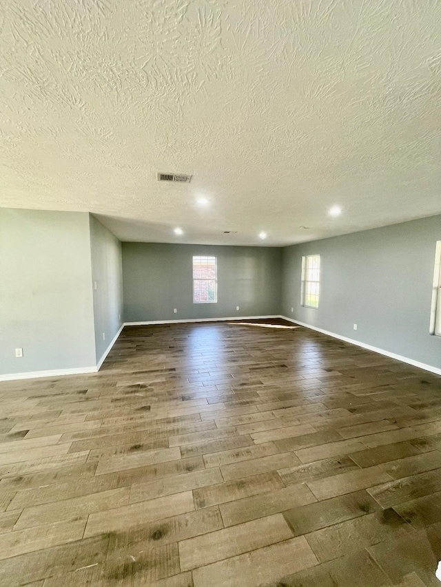 empty room featuring wood-type flooring and a textured ceiling