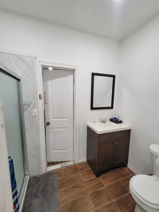 bathroom with a shower with door, vanity, and toilet