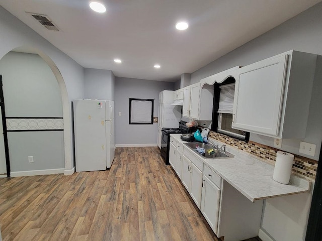 kitchen featuring electric range, white fridge, white cabinetry, and sink