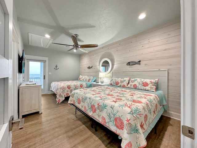 bedroom featuring hardwood / wood-style flooring, ceiling fan, and wood walls