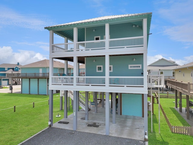 beach home featuring a carport, a balcony, a garage, and a front lawn