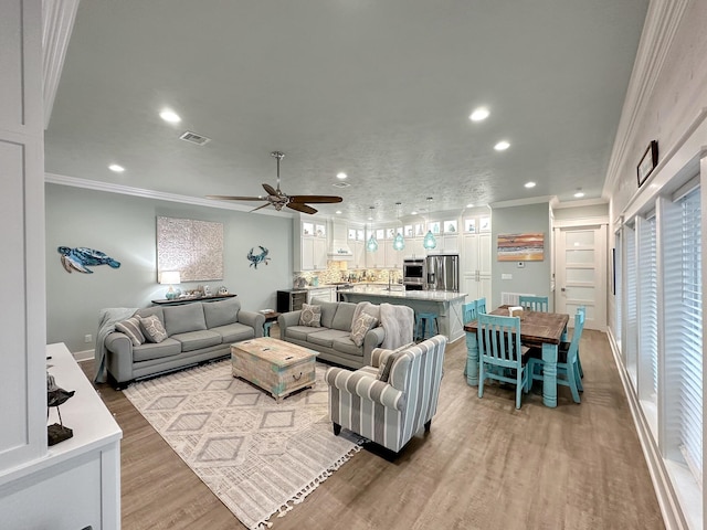 living room featuring crown molding, light hardwood / wood-style flooring, and ceiling fan