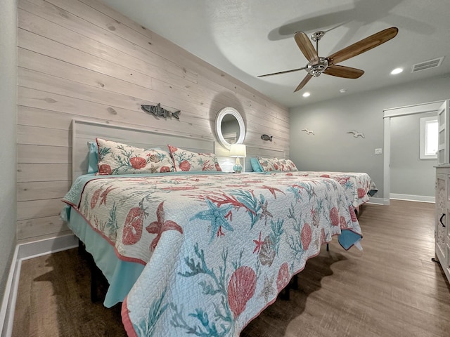 bedroom featuring ceiling fan and wood walls