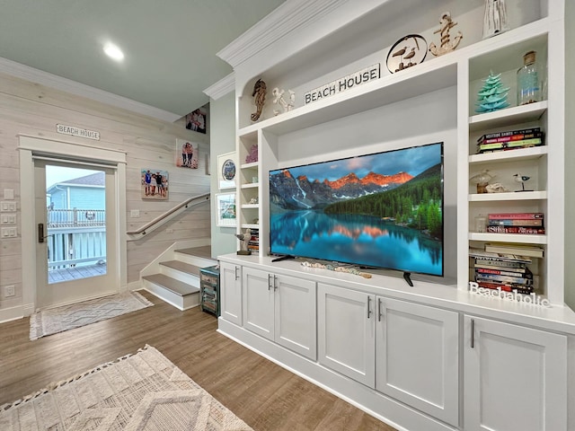 interior space featuring wood walls, hardwood / wood-style floors, and ornamental molding