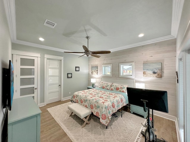 bedroom with ceiling fan, wood-type flooring, ornamental molding, and wooden walls