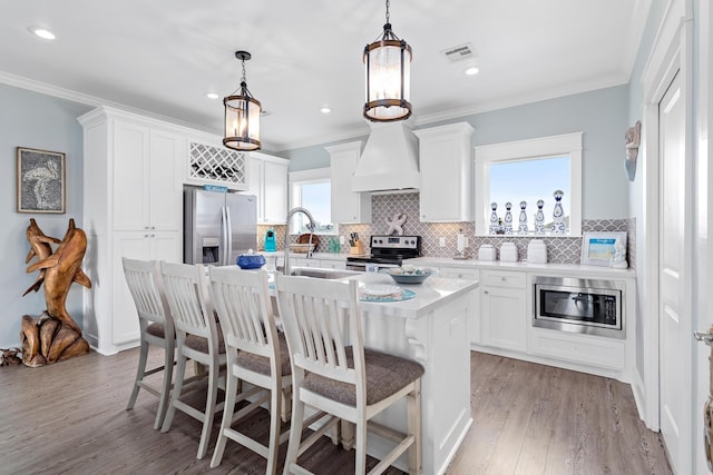 kitchen featuring white cabinets, custom range hood, sink, and appliances with stainless steel finishes