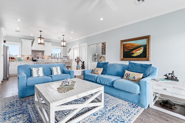 living room with crown molding, light hardwood / wood-style flooring, and ceiling fan