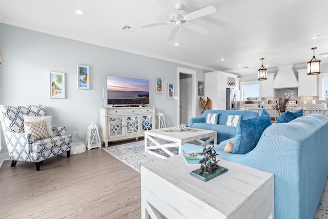 living room with ceiling fan, light hardwood / wood-style flooring, and crown molding