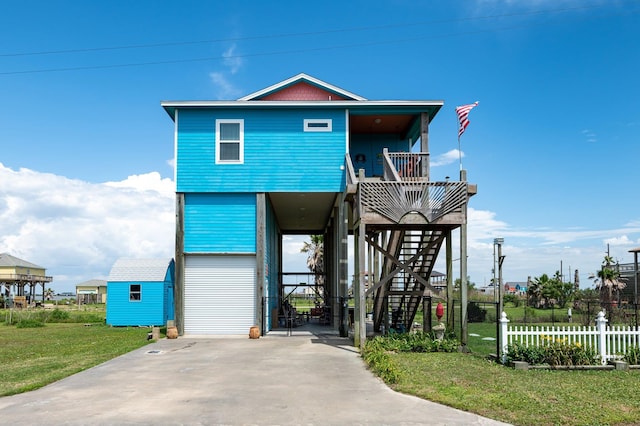 raised beach house featuring a front lawn and a storage shed