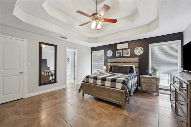 265 Callie Ln, Orange, TX 77632 - bedroom with a tray ceiling, baseboards, a ceiling fan, and ensuite bath