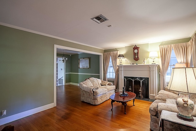 living room with a high end fireplace, wood-type flooring, a notable chandelier, and ornamental molding