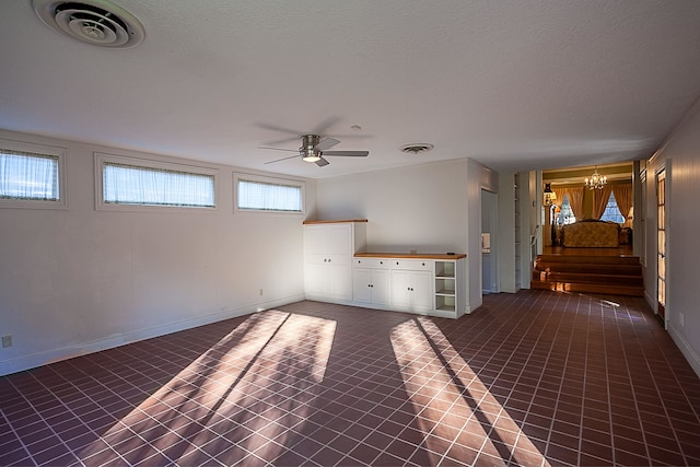 unfurnished living room with a textured ceiling and ceiling fan with notable chandelier