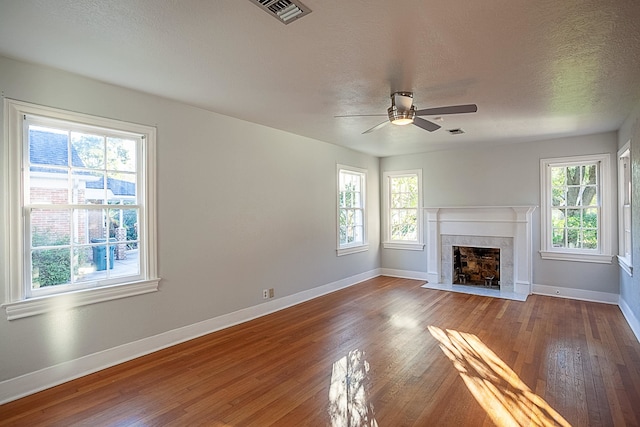 unfurnished living room featuring hardwood / wood-style flooring, ceiling fan, a healthy amount of sunlight, and a textured ceiling