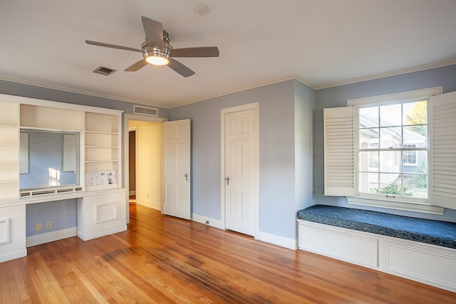 unfurnished bedroom featuring hardwood / wood-style floors, ceiling fan, built in desk, and ornamental molding