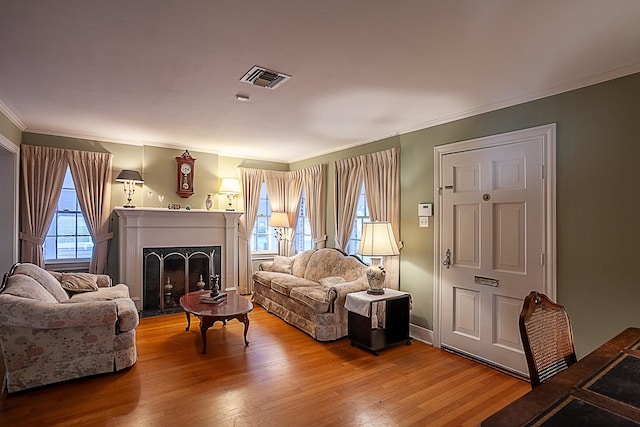 living room with wood-type flooring, ornamental molding, and a high end fireplace